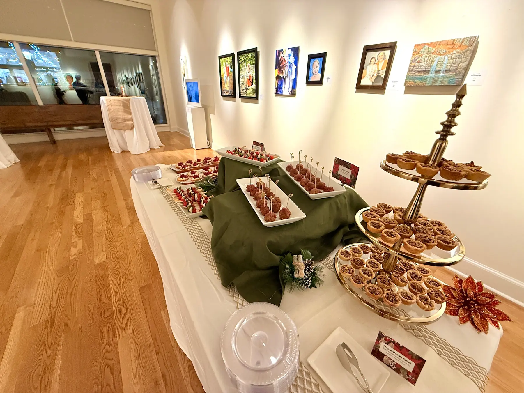 Canapes on tiered stands and a green-draped table set for a reception in an art gallery