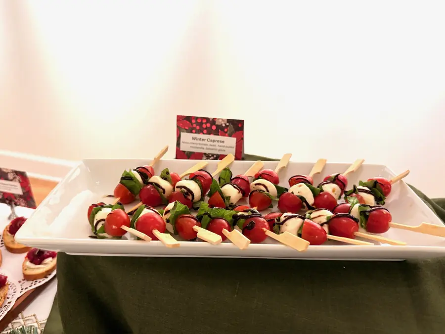 Caprese skewers of tomato, mozzarella and basil on a white platter
