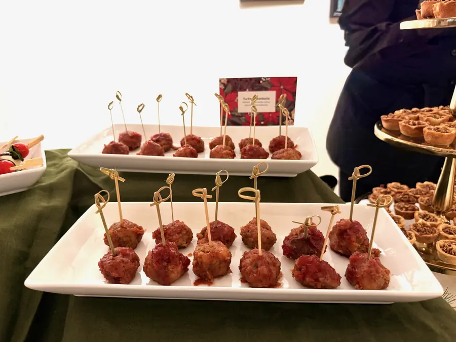 Glazed meatball canapes on skewers, arranged on a white platter