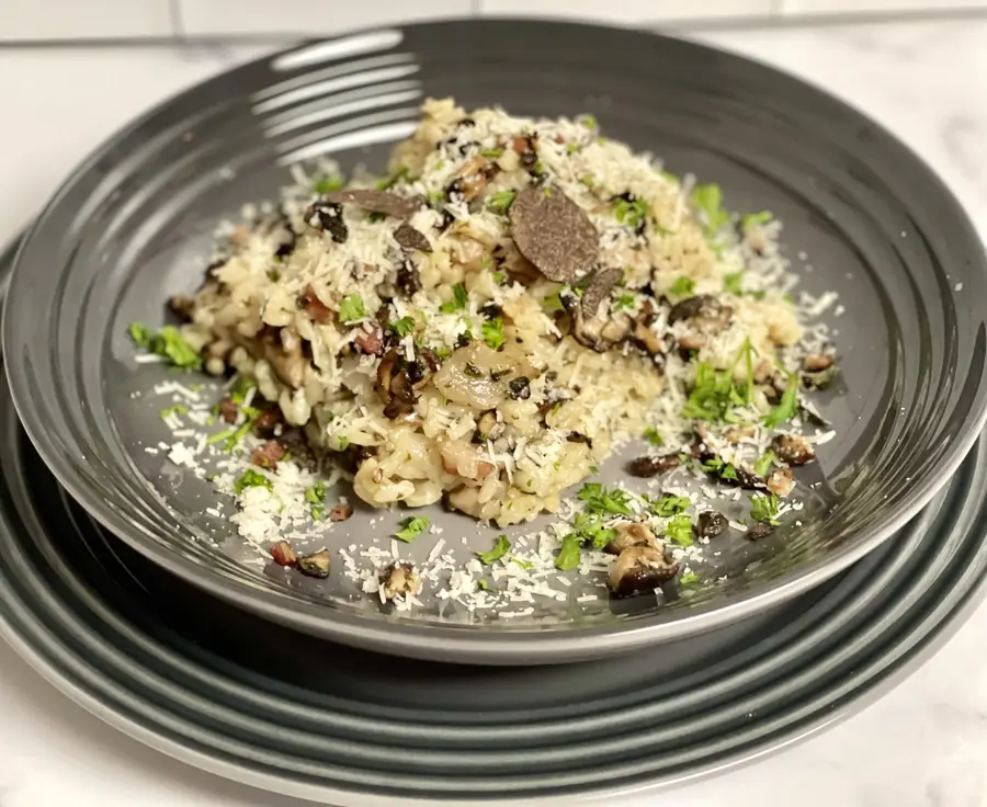 Mushroom risotto finished with shaved black truffle on dark stoneware