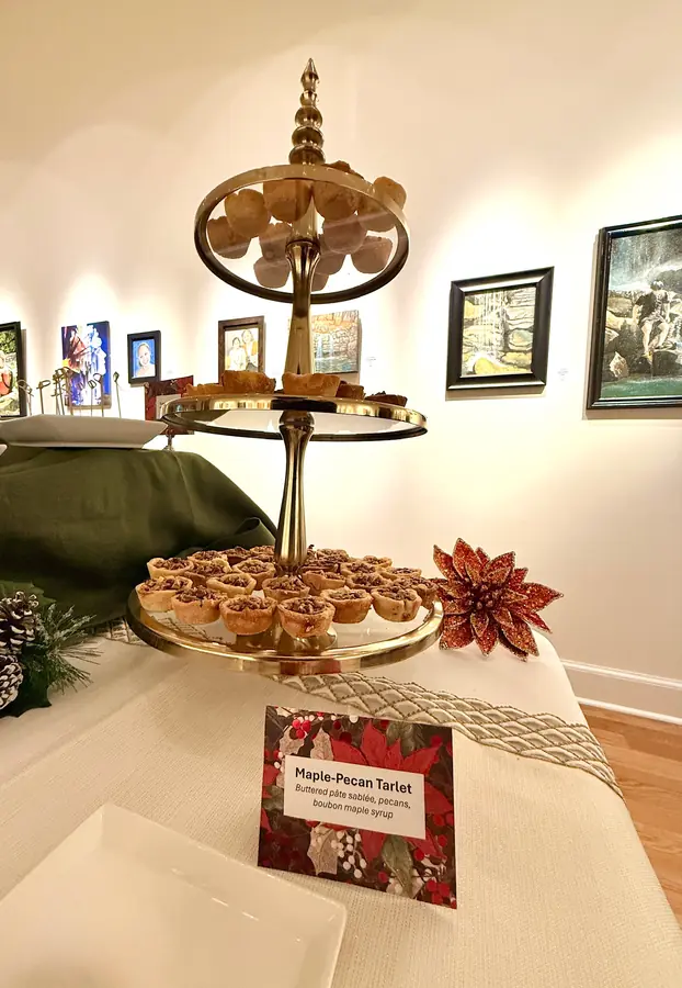 A tiered stand of tartlets with a printed menu card at a gallery reception