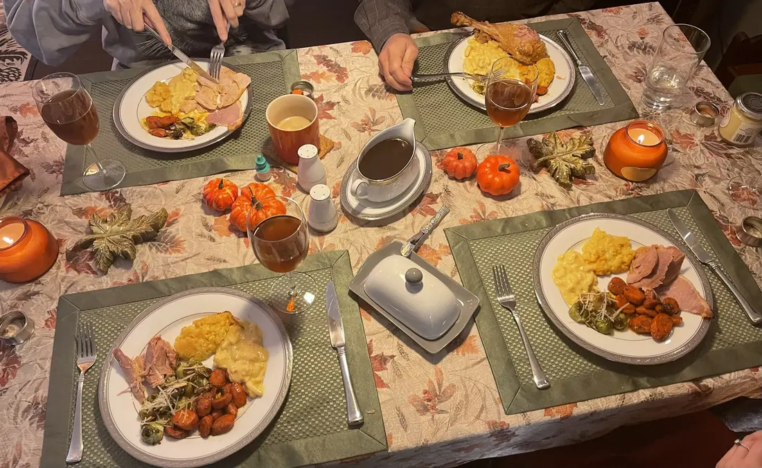 A holiday table laid with full place settings, plated dinners and autumn decorations