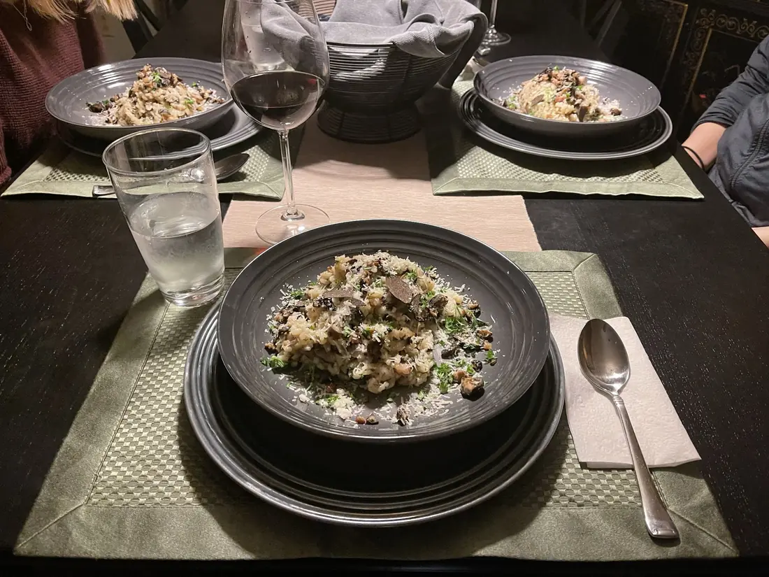 A table set for two with wine glasses and plated risotto on dark stoneware
